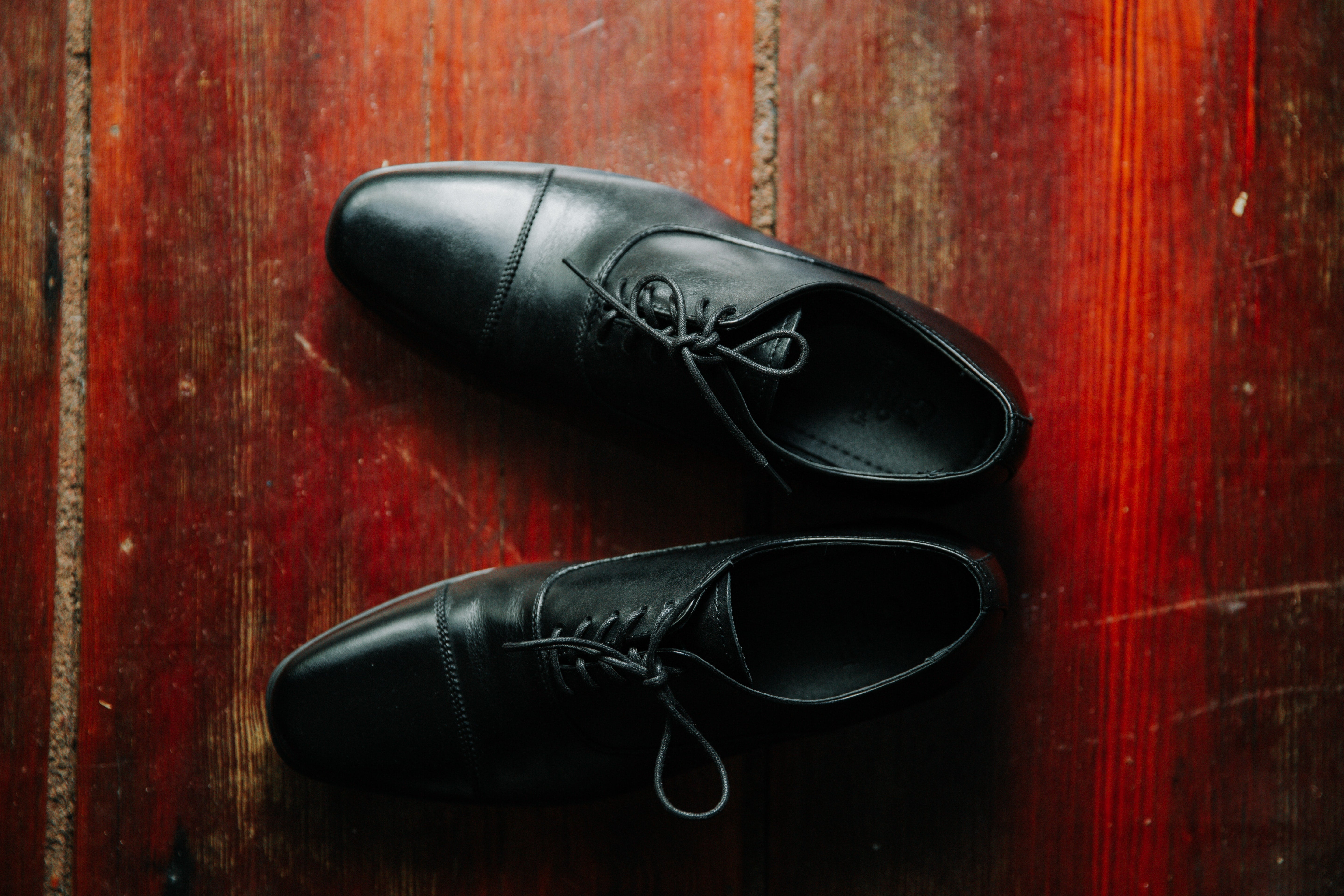black Oxford shoes on reddish brown wooden floor