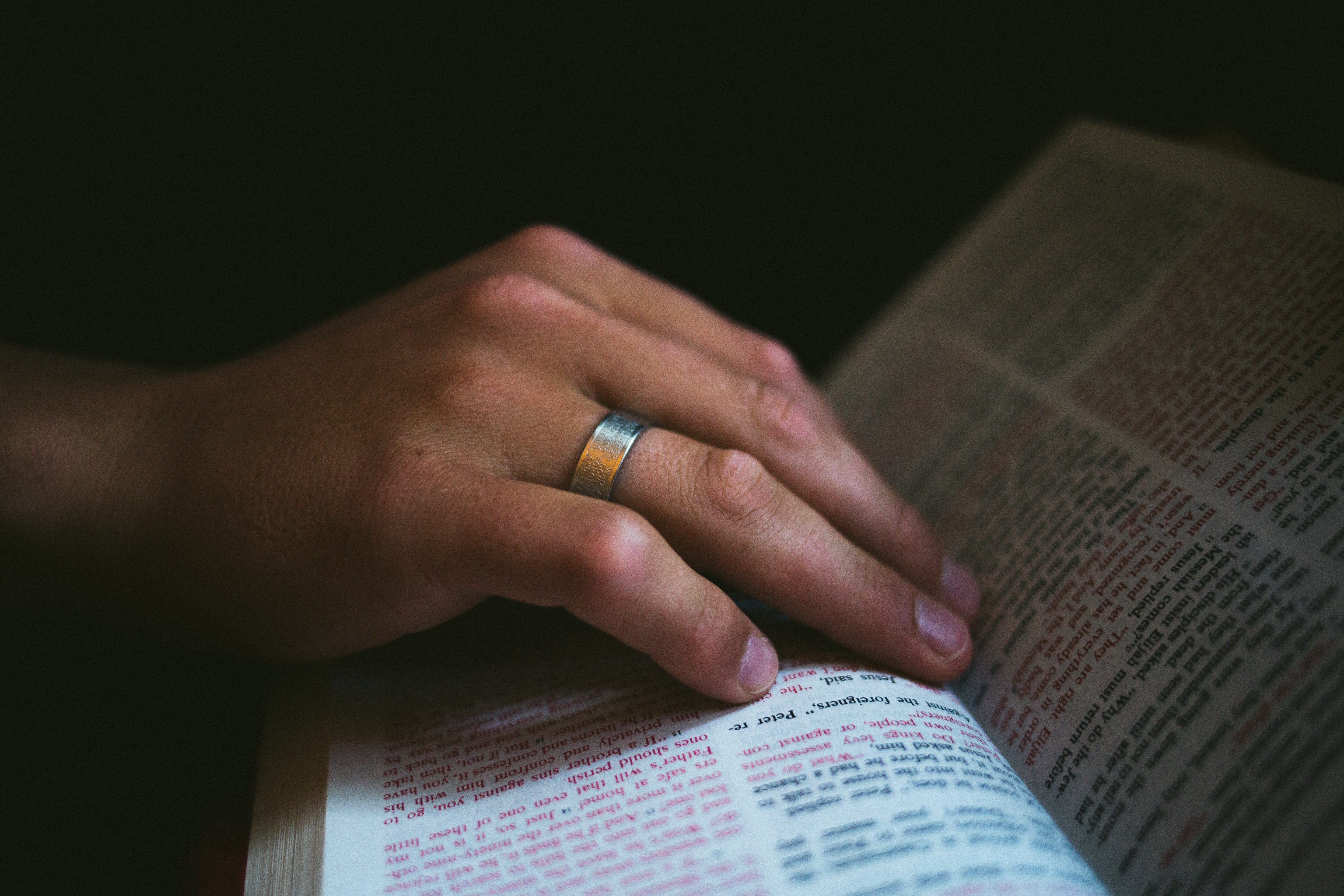 man's hand with stainless steel ring on an open book