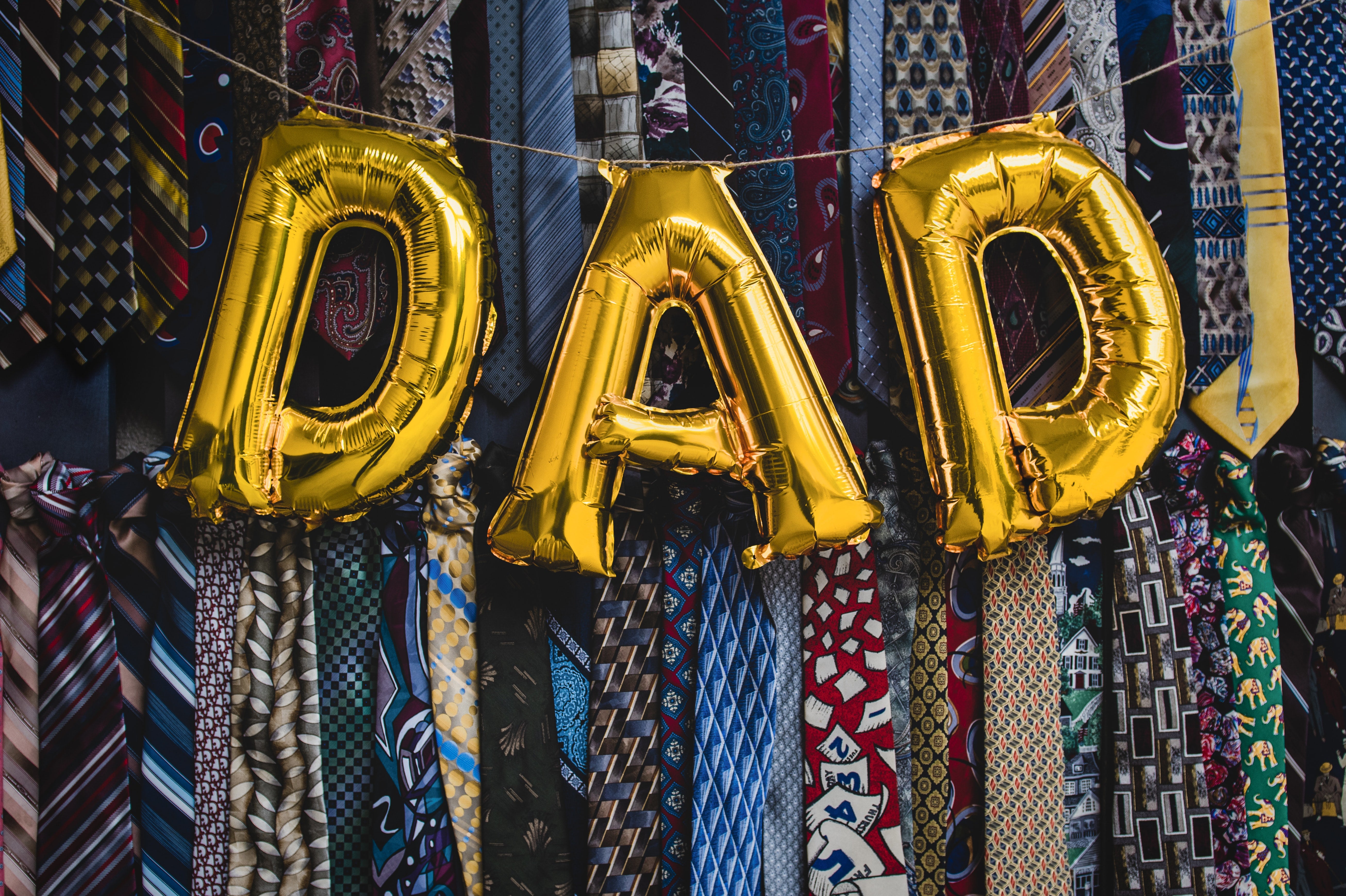 gold foil balloons spelling out DAD with ties as background