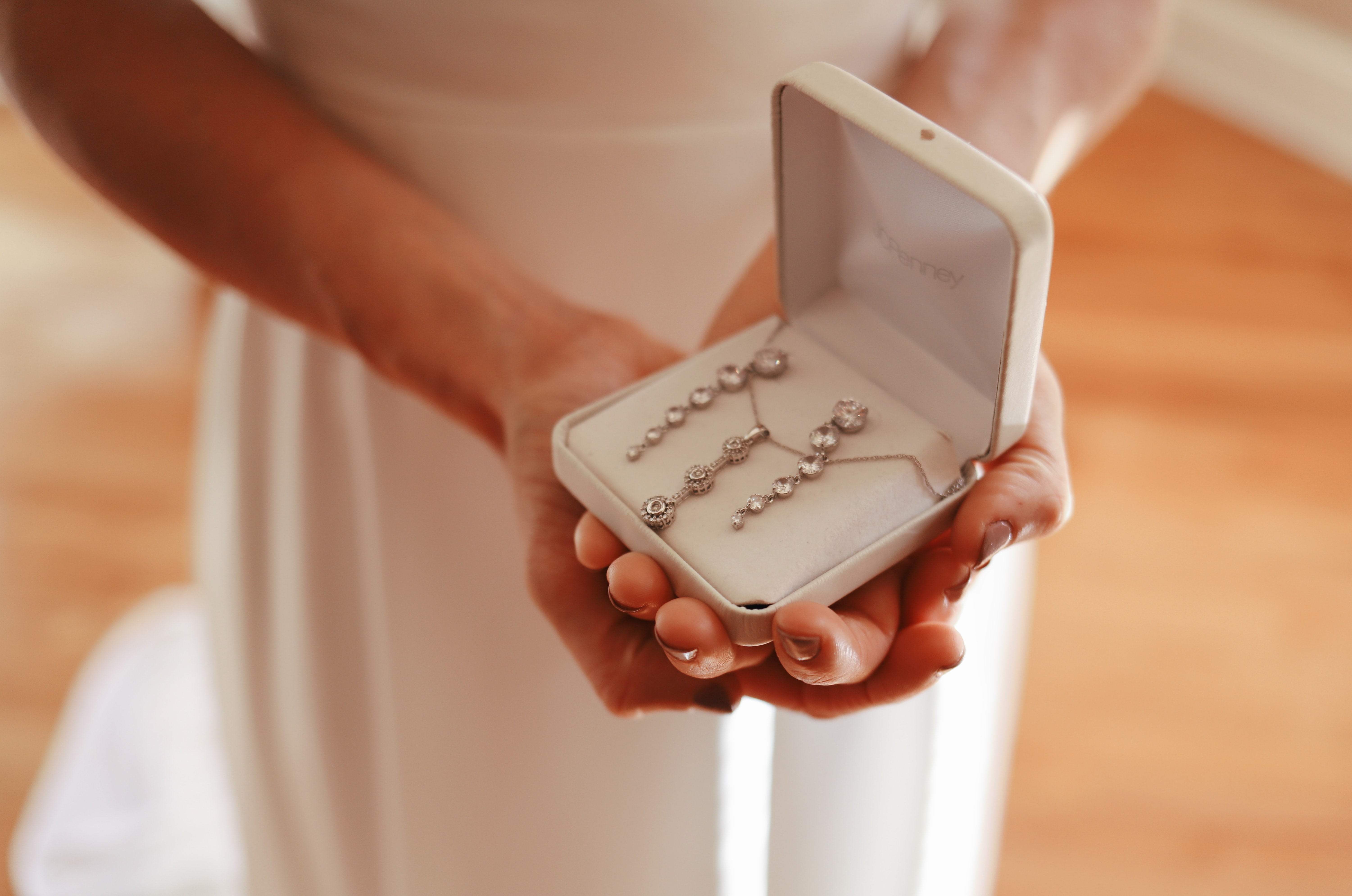 woman in white holding a jewelry box with swarovski pendant necklace and swarovski drop earrings