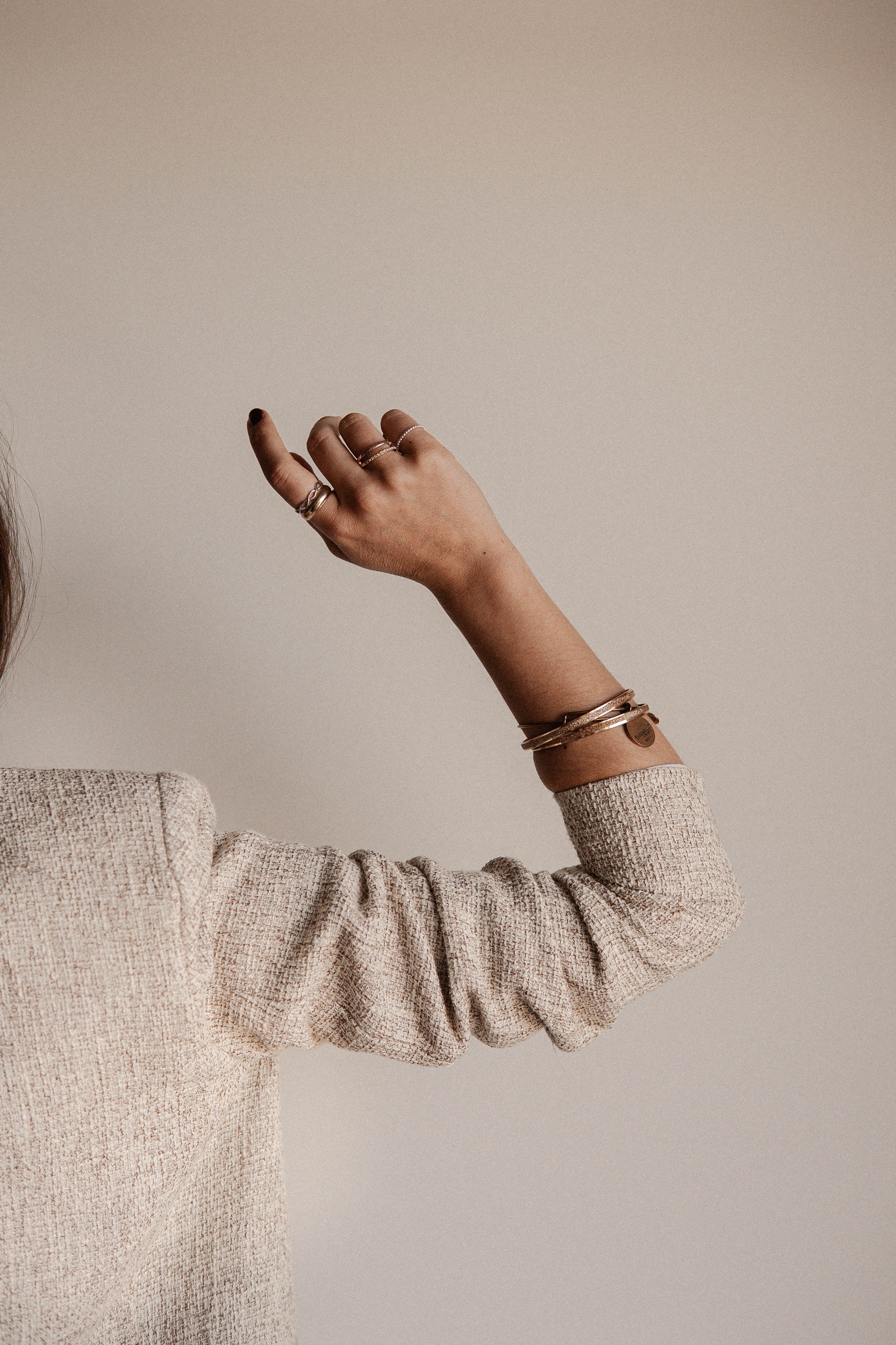 woman's hand and arm wearing coffee-plated fashion rings and bangles