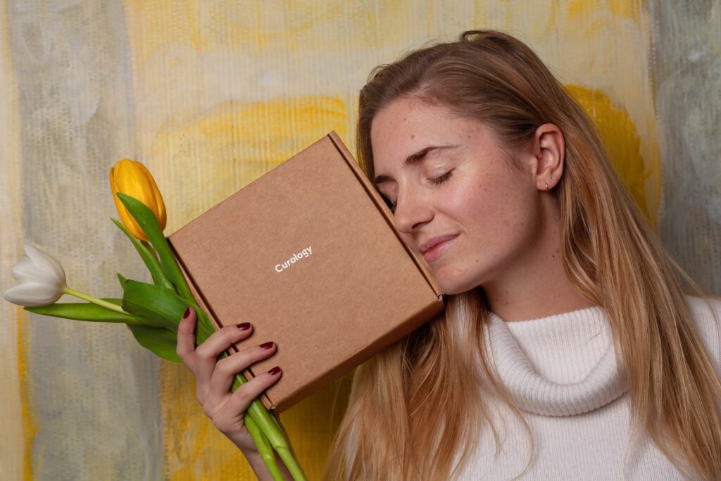 woman smiling with her eyes closed holding a subscription box near her face