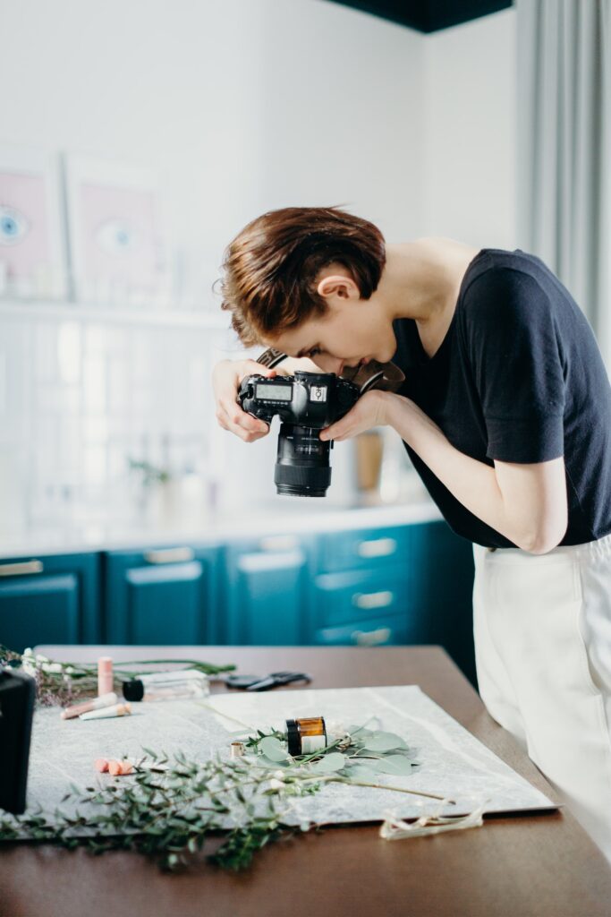 woman-wearing-black-shirt-taking-picture-of-flowers-on-top-of-table