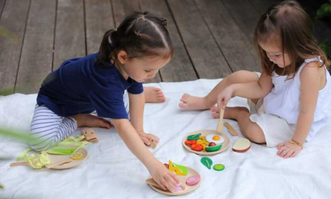 Girls play with toy food set from PlanToys