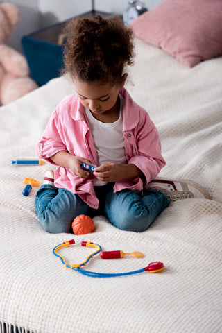 Toddler girl with doctor set for pretend play - imaginative play development benefits