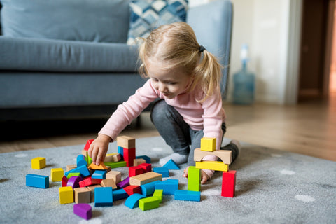 Girl builds a house with colorful wooden blocks