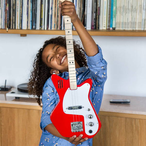 young girl smiles and holds here loog electric guitar