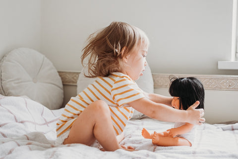 Toddler girl plays with doll - importance of pretend play to child development