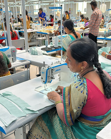 Workers sewing together a button-up collared shirt