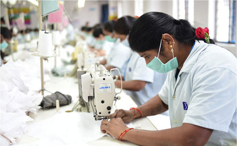 A worker sewing a garment at Suvastra