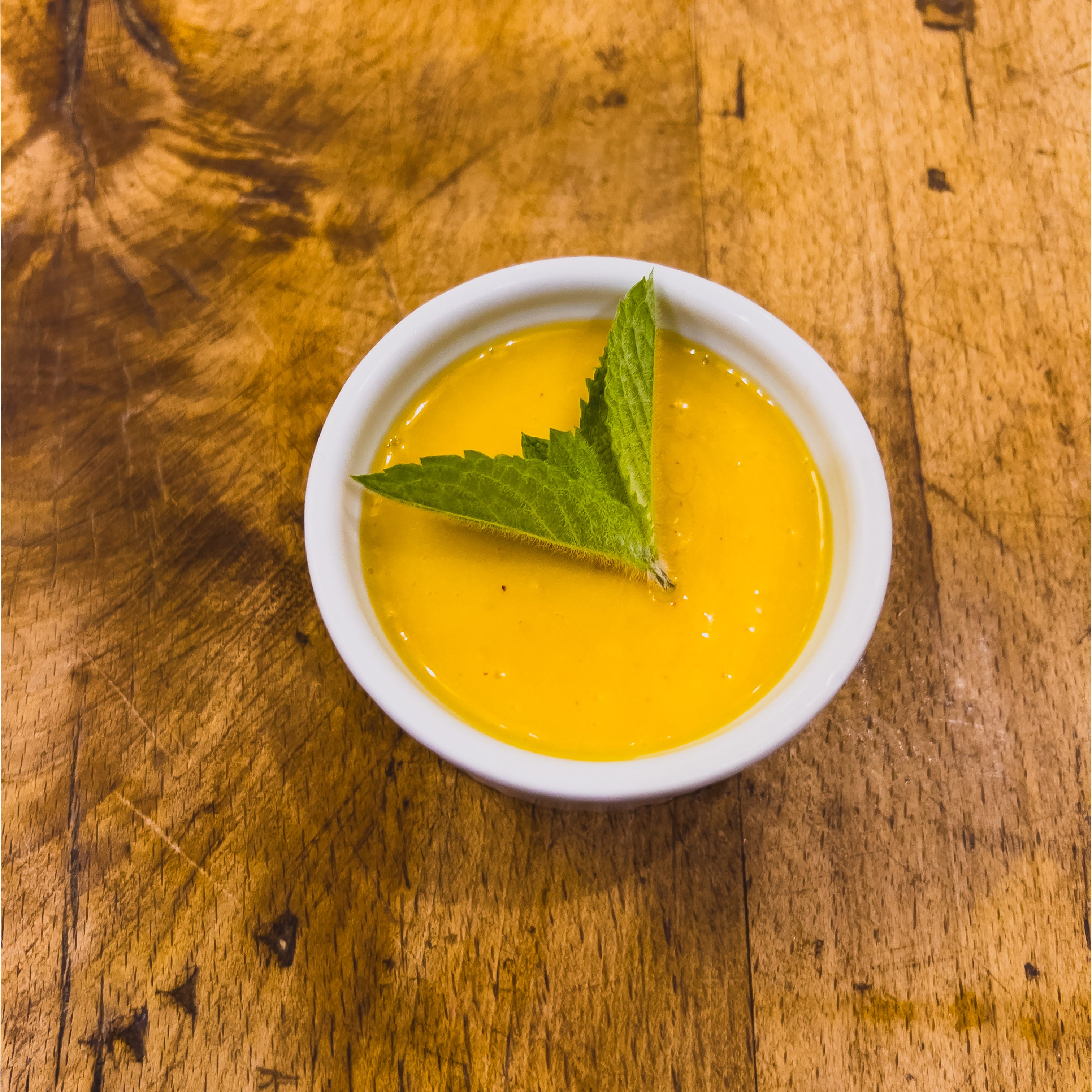 A Small Ramekin Filled With a Rich Peach and Olive Oil Gelato, Topped With a Mint Leaf