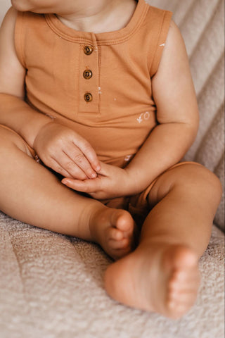 Image d'un bébé assis sur un canapé, les mains posées sur ses genoux
