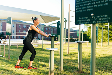 woman stretching on outdoor fitness equipment