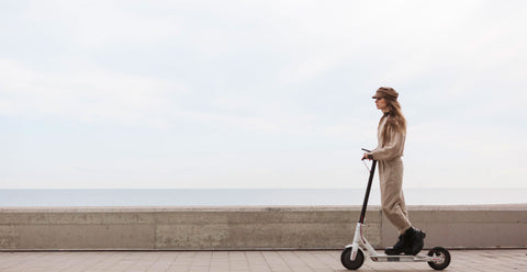 Woman rides an electric scooter with a view of the sea