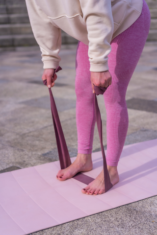 woman with yoga strap around feet 