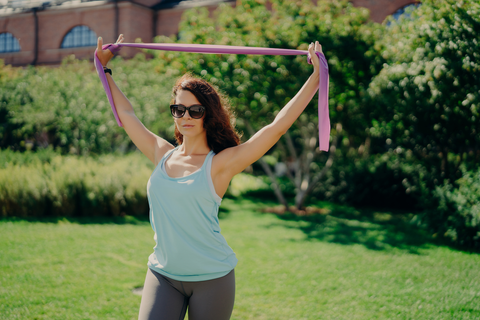 woman stretching her arms with a yoga strap outdoors