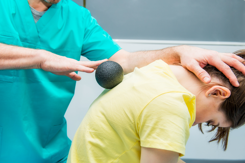 doctor using black massage ball on patients back