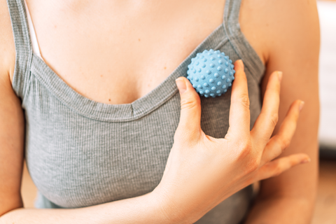 woman using massage ball on chest