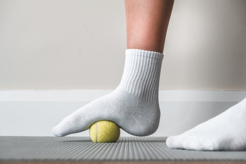 person using massage ball on foot