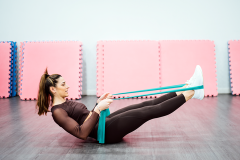 fit woman doing boat pose with yoga straps