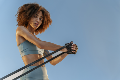 fit woman in workout gear using a resistance band with one hand