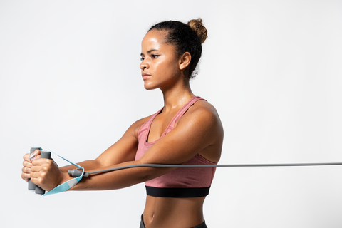 woman in workout gear doing a chest press with resistance bands