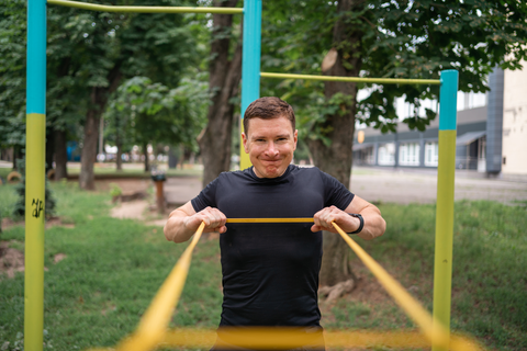 man doing a chest fly outdoor with resistance bands