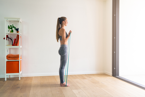 woman doing a standing back fly with resistance band