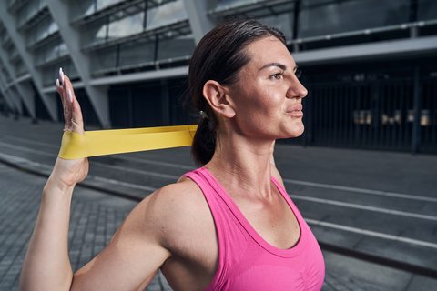 fit woman using resistance bands outdoors