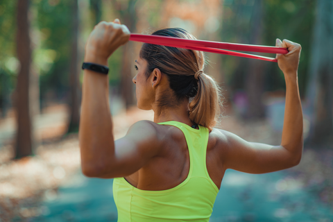 fit woman using resistance bands behind neck