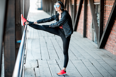 woman on jeans stretching legs on the railings