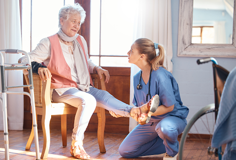 senior woman seated having a foot massaged by a nurse