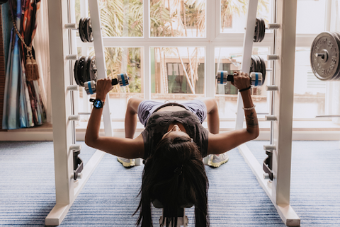 woman lifting weights on back at gym