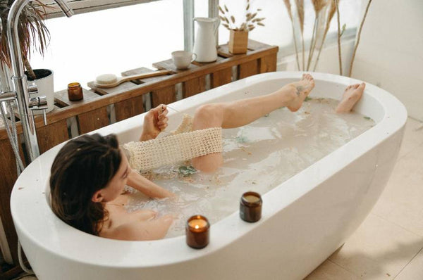 A woman relaxing in the bath with candles next to her