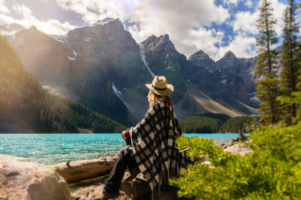 Person relaxing by a lake at the foot of the mountains