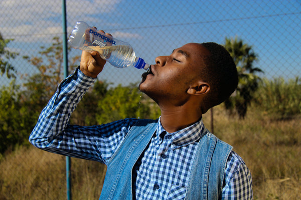 A man drinking a bottle of water on a sunny day outside