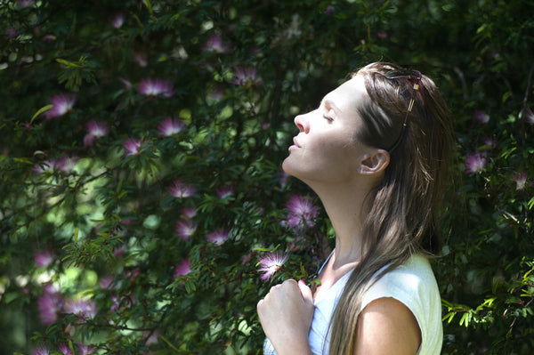 Woman holding a flower practising deep breathing outside