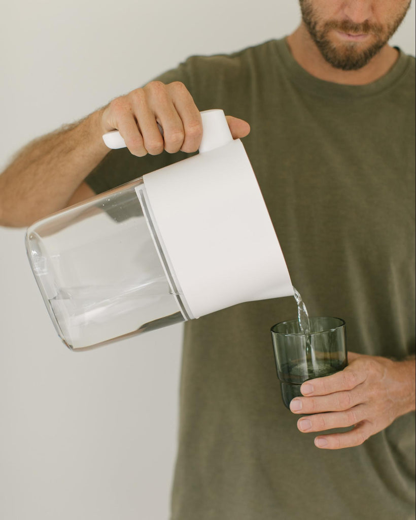 Man pouring water into a glass from a filter.