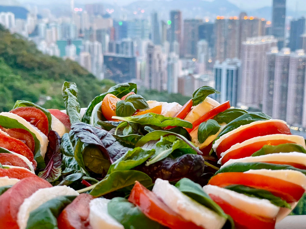 Closeup of salad on a plate with a cityscape in the background.
