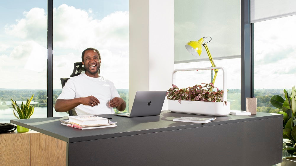 Man laughing while at his office desk, with the Smart Garden 9 close by.
