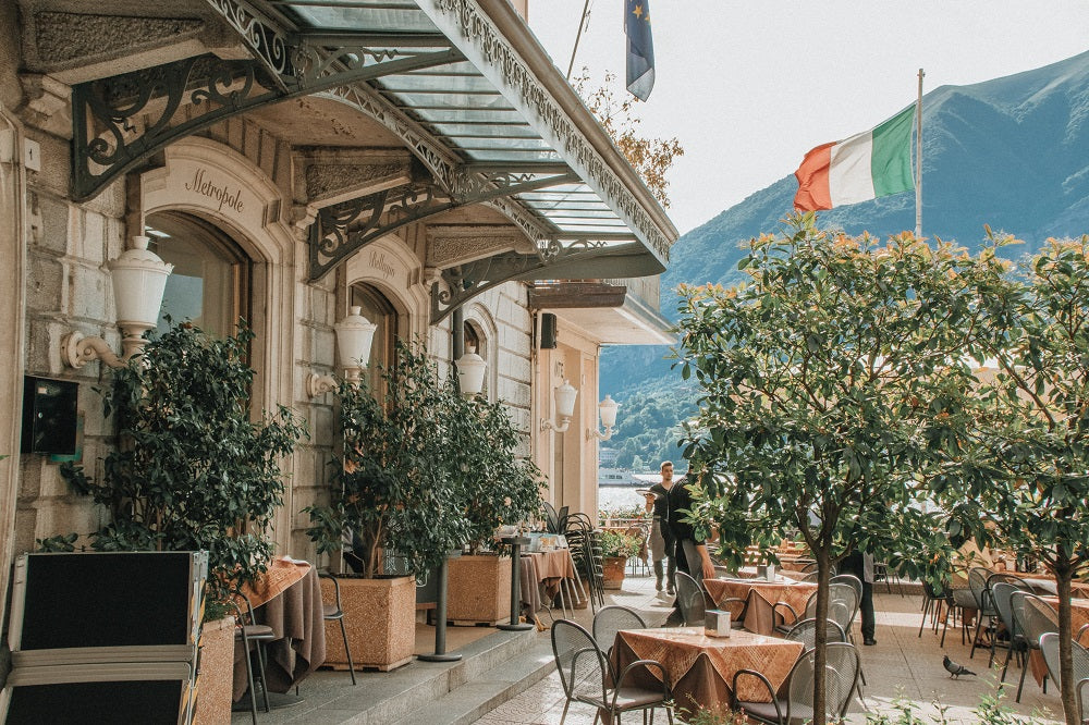Outdoor view of an Italian restaurant with the Italian flag nearby.