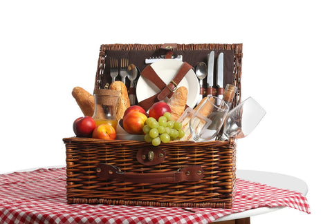 A wicker picnic basket filled with a variety of fresh fruit and bread.