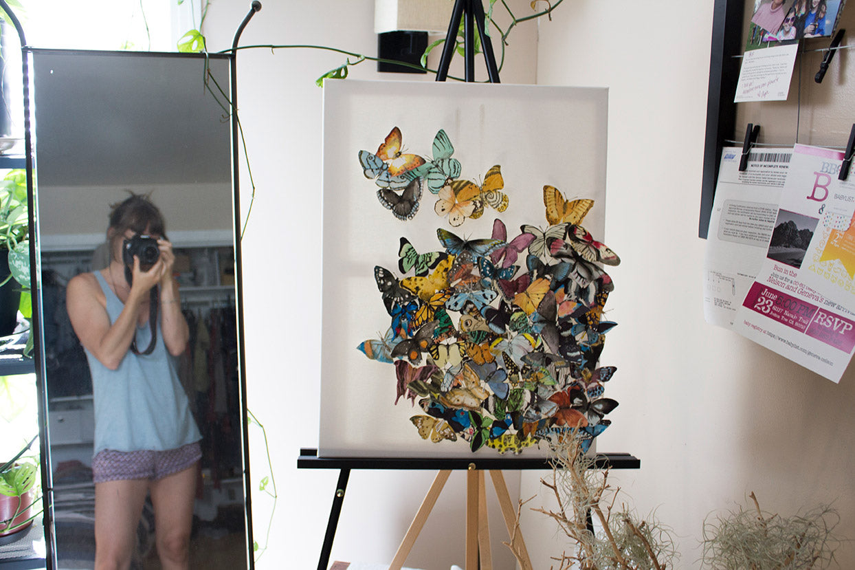 Artist Bridget Kilgallon - Self Portrait in front of a mirror with watercolor butterfly artwork.