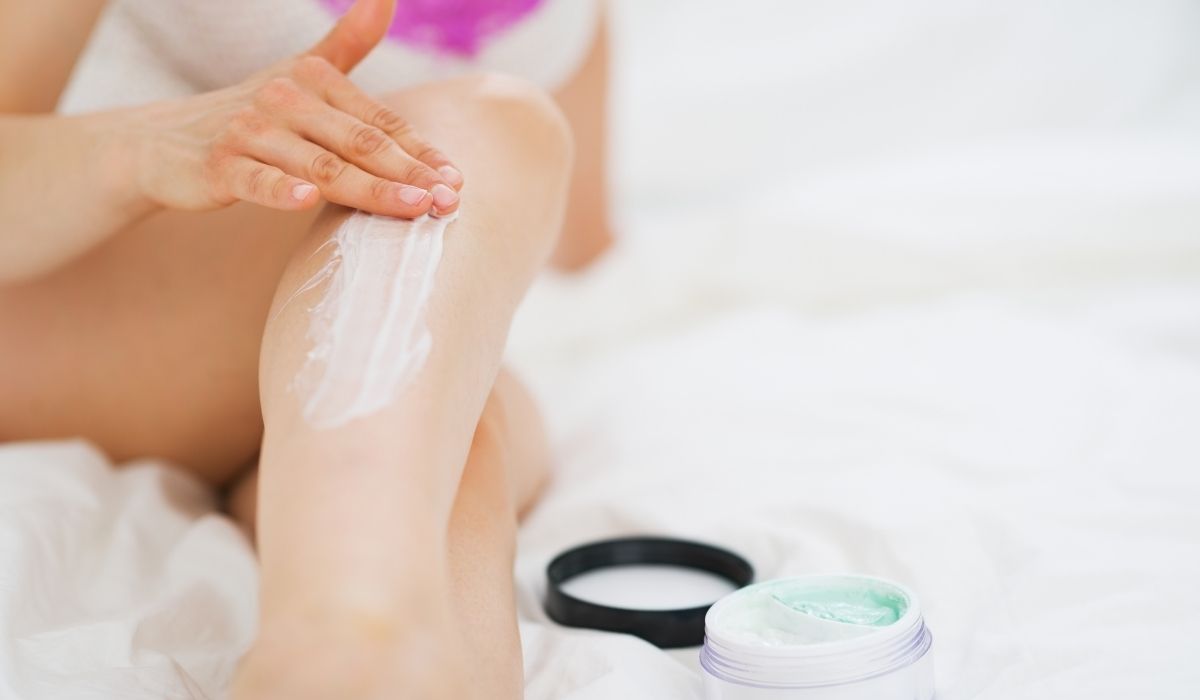 Woman applying cream on her legs