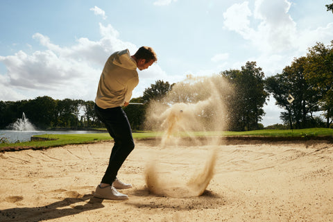 Golfer hitting shot out of bunker