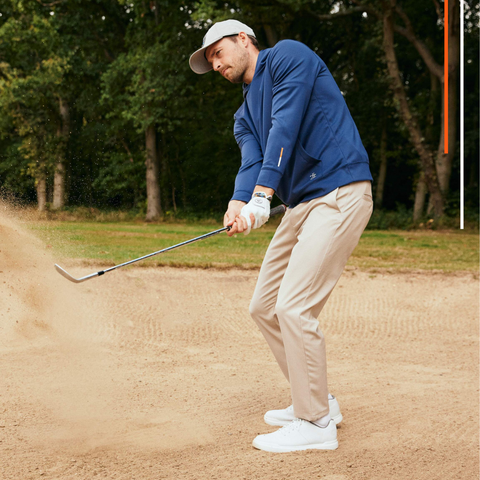 Golfer wearing hoodie taking bunker shot