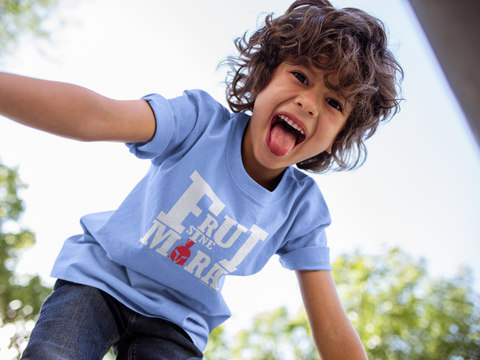Petit garçon heureux et tirant la langue, habillé d’un t-shirt bleu ciel où est écrit en gros et en lettres capitales Frui Sine Mora