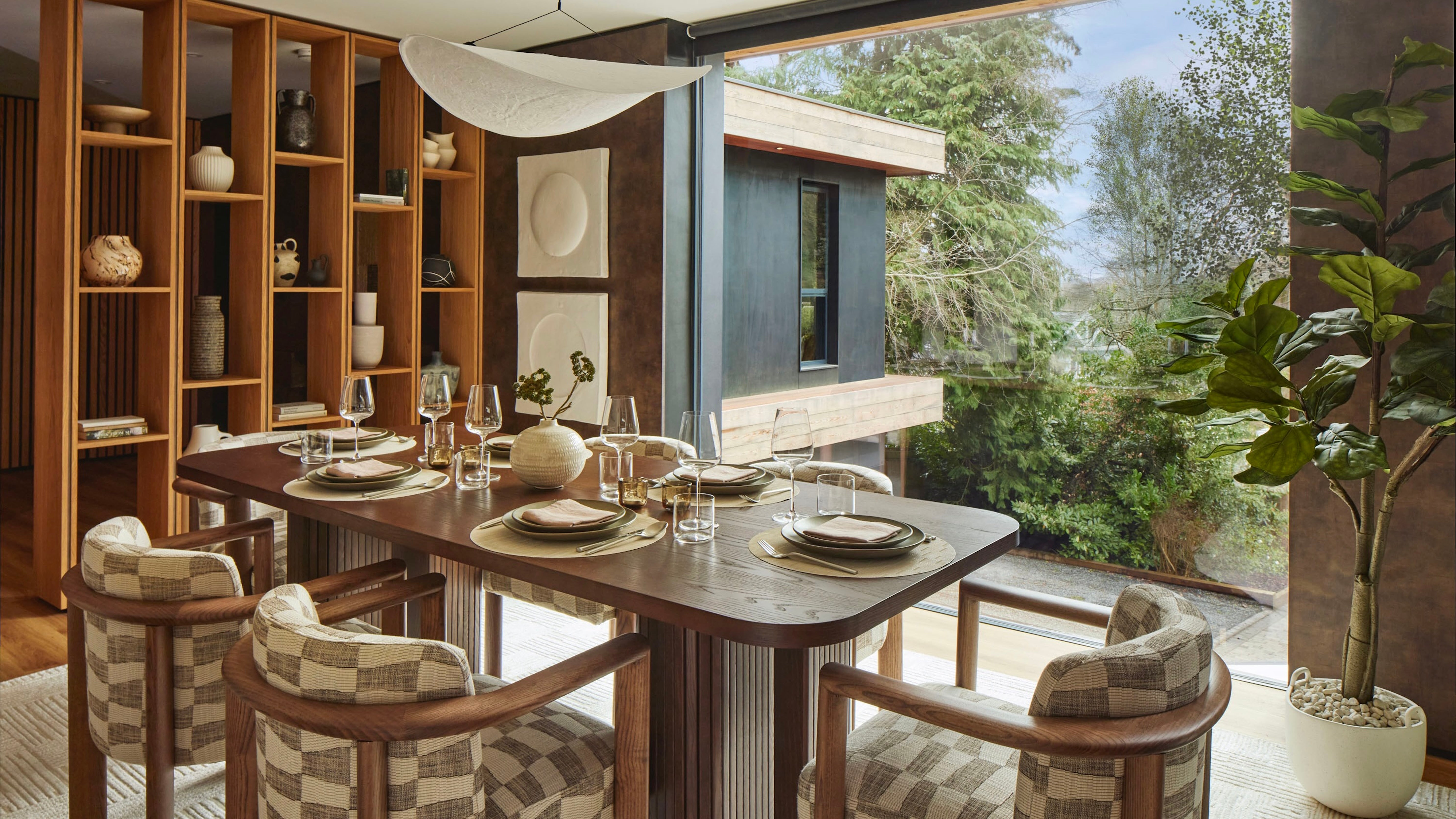 <p><strong>Dining Room</strong></p><p>Curved upholstered tub chairs and a solid wood table offer floor-to-ceiling views of thriving greenery under the falling leaf of a paper lightshade.</p>