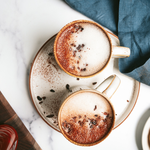 Mugs of cacao-maca latte (coffee alternative) on a saucer.