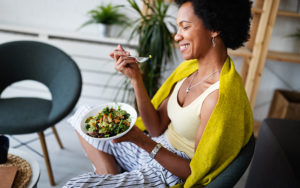 Woman smiling eating a healthy vegetables bowl